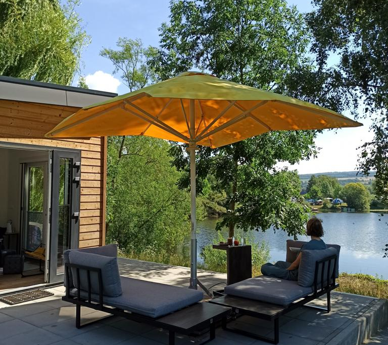 Loungemöbel unter Sonnenschirm mit Seeblick