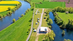 Drohnenaufnahme des Wohnmobilstellplatzes Weserbogen zwischen Weser und Uferlandschaft in Höxter-Godelheim.