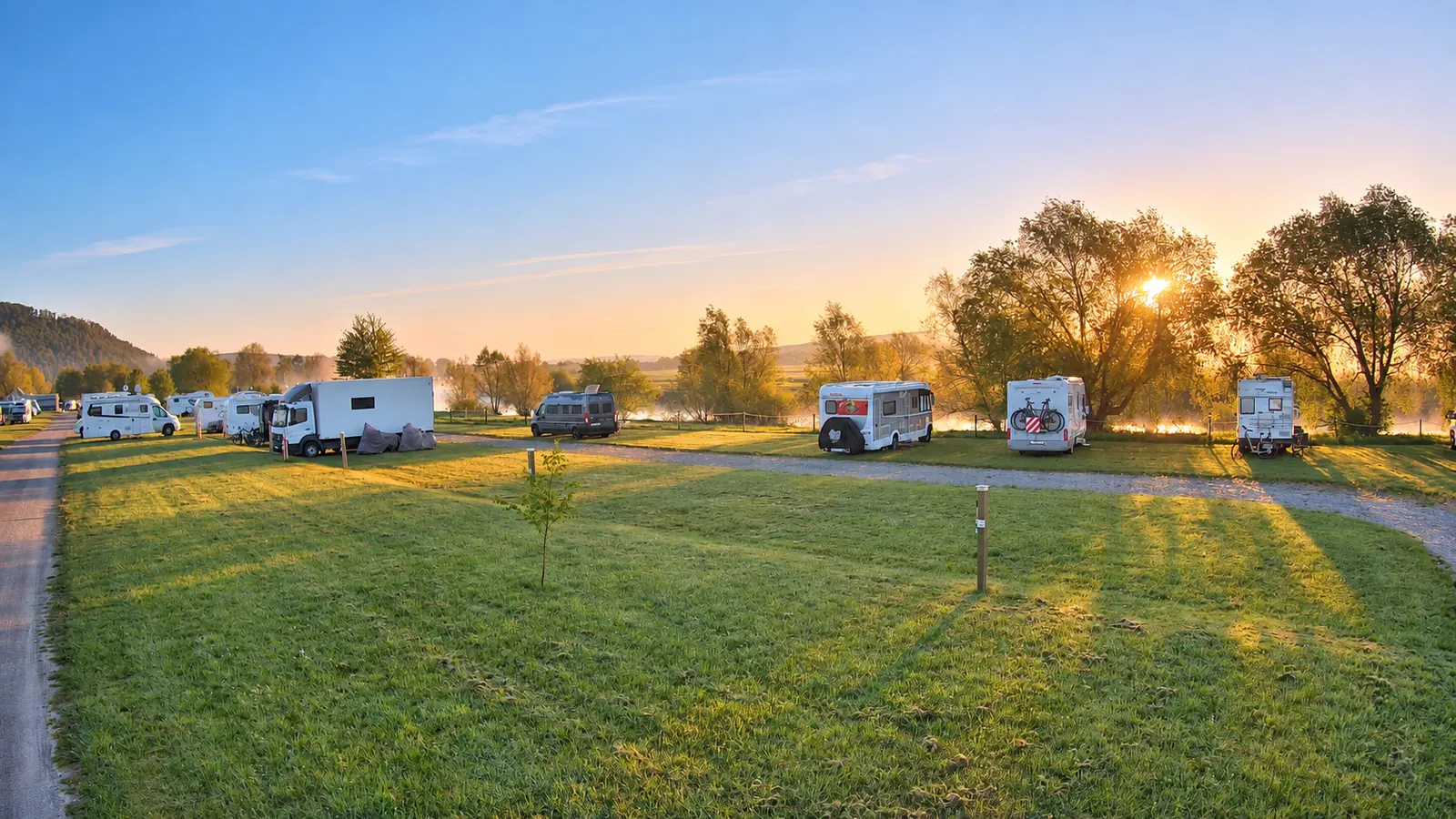 Wohnmobilstellplatz am Weserbogen bei Sonnenaufgang mit warmem Morgenlicht und Blick auf den Fluss.