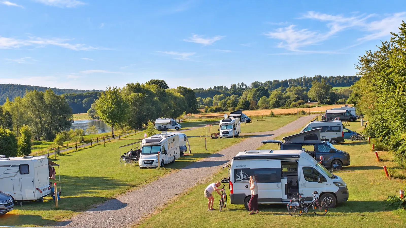 Sonniger Wohnmobilstellplatz Weserbogen mit gepflegten Flächen und Blick auf die Weser.